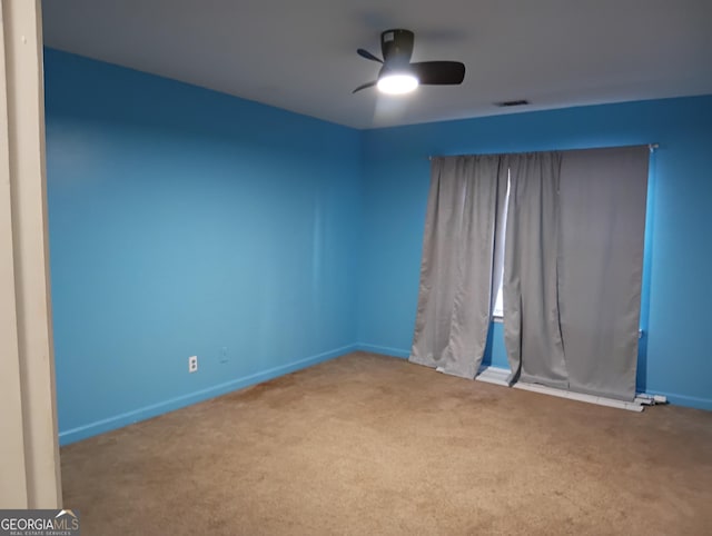 carpeted spare room featuring visible vents, baseboards, and a ceiling fan