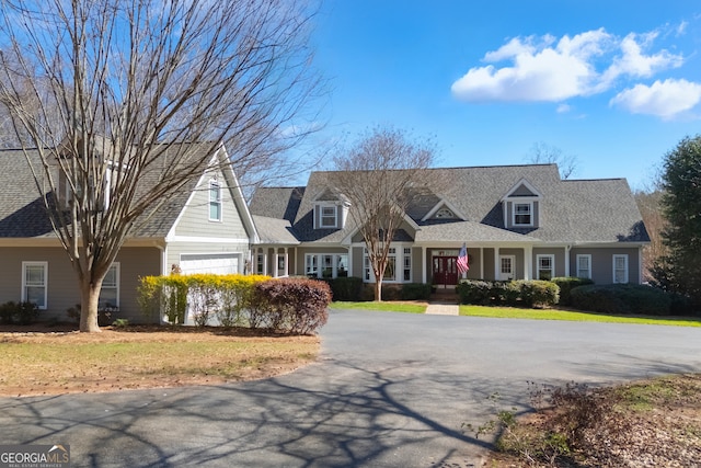 cape cod house featuring aphalt driveway and a shingled roof