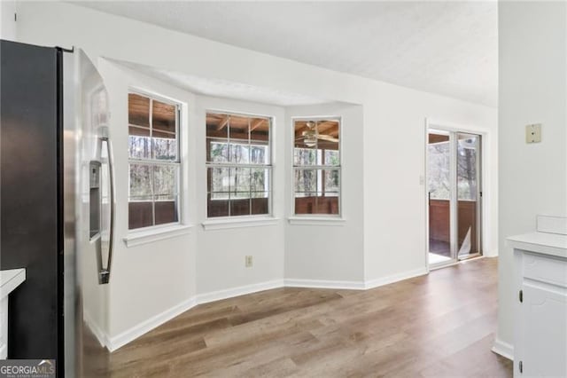 unfurnished dining area featuring wood finished floors and baseboards