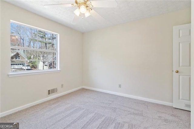 empty room featuring a ceiling fan, carpet, visible vents, and baseboards