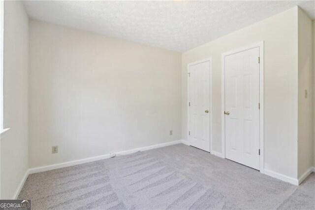 unfurnished bedroom with carpet, baseboards, and a textured ceiling