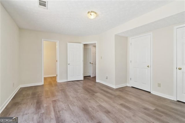 unfurnished bedroom with visible vents, baseboards, and wood finished floors