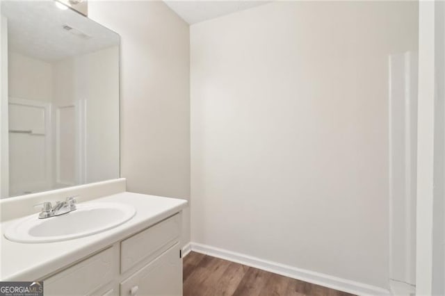 bathroom featuring vanity, wood finished floors, and baseboards