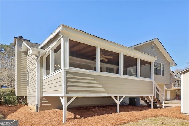 view of property exterior with central AC, a sunroom, and a chimney