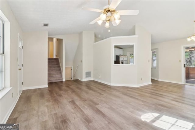 unfurnished living room with visible vents, stairway, baseboards, and wood finished floors