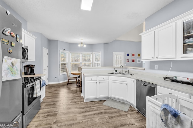 kitchen featuring appliances with stainless steel finishes, white cabinetry, a peninsula, and a sink