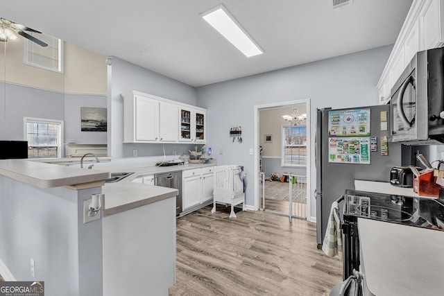 kitchen with a sink, light wood-style floors, white cabinetry, and stainless steel appliances