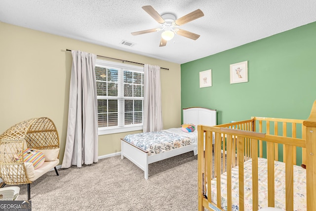 carpeted bedroom featuring visible vents, baseboards, a textured ceiling, and ceiling fan