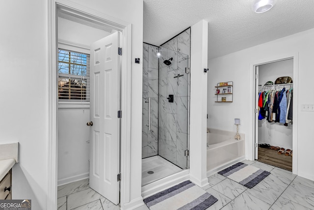 full bath featuring marble finish floor, a textured ceiling, a marble finish shower, a bath, and a spacious closet