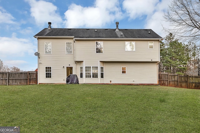 back of house with a fenced backyard and a yard