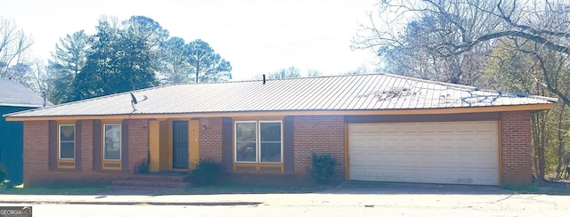 view of front of property featuring brick siding, an attached garage, and metal roof