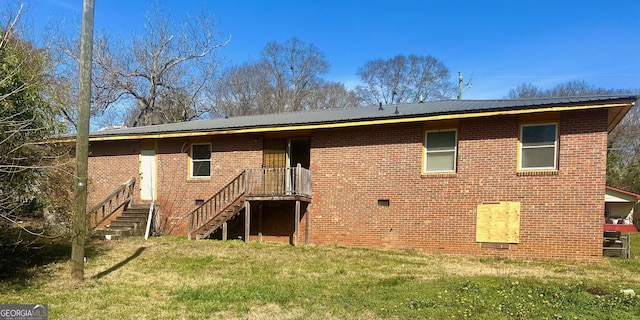 back of property featuring a lawn, brick siding, and metal roof