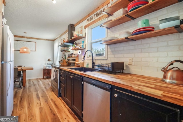 kitchen with open shelves, light wood-style flooring, a sink, butcher block countertops, and stainless steel appliances