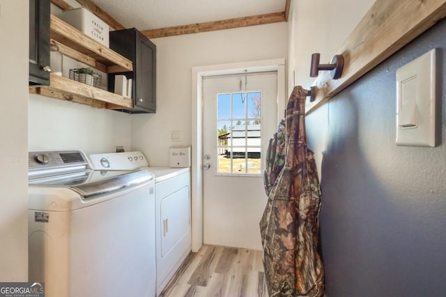 laundry room featuring separate washer and dryer, cabinet space, and light wood-style floors