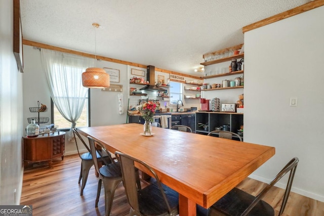 dining room featuring light wood-style floors, baseboards, and a textured ceiling