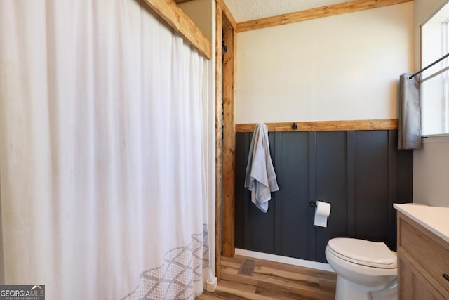 full bathroom with a textured ceiling, toilet, vanity, and wood finished floors