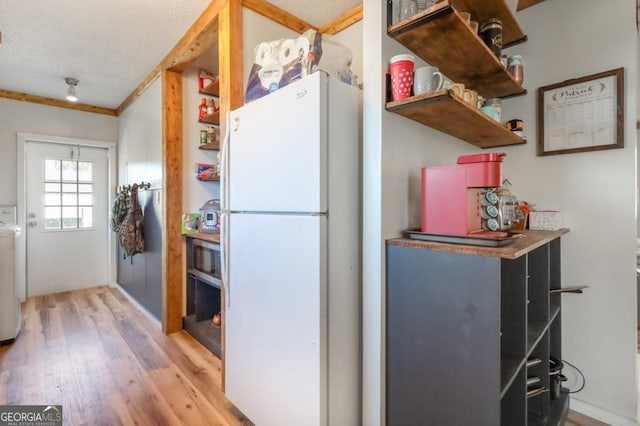 kitchen featuring open shelves, a textured ceiling, light wood-style flooring, and freestanding refrigerator