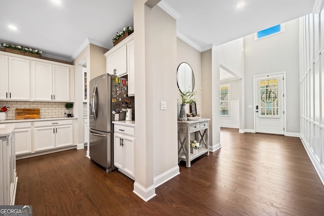 kitchen with backsplash, crown molding, stainless steel refrigerator with ice dispenser, dark wood-style floors, and white cabinets