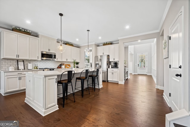 kitchen with backsplash, appliances with stainless steel finishes, a breakfast bar area, and white cabinetry