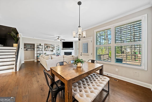 dining area featuring dark wood finished floors, visible vents, a fireplace, and crown molding