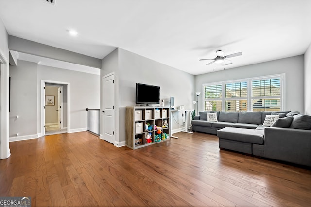 living room with ceiling fan, baseboards, and wood finished floors