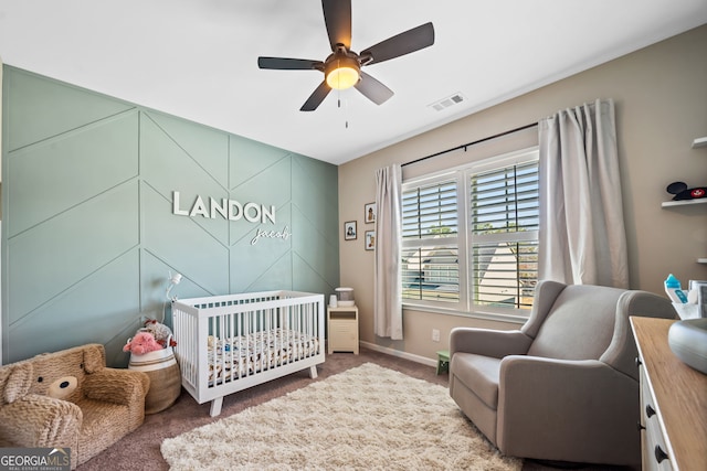 bedroom with visible vents, a crib, a ceiling fan, carpet flooring, and baseboards