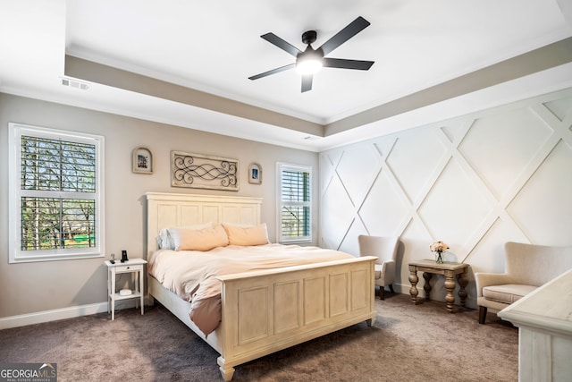 bedroom with visible vents, baseboards, ornamental molding, a raised ceiling, and dark carpet