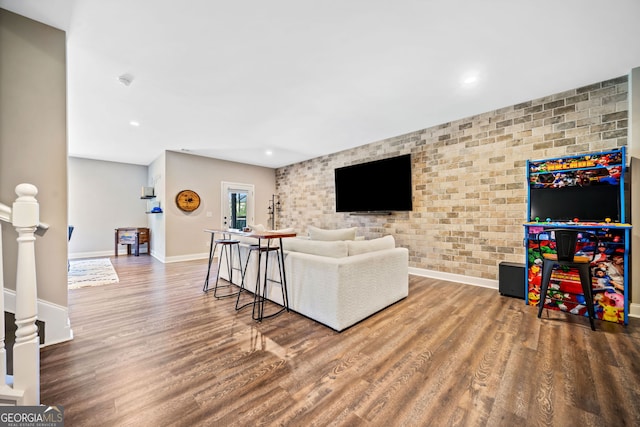 living area featuring recessed lighting, brick wall, baseboards, and wood finished floors