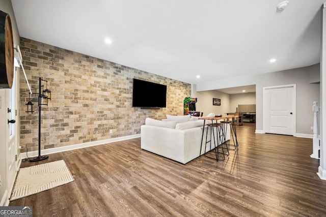 living room featuring recessed lighting, wood finished floors, baseboards, and brick wall