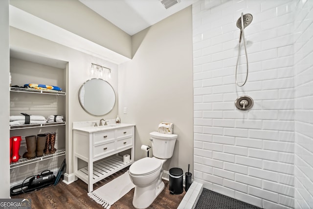 full bathroom with toilet, wood finished floors, visible vents, and tiled shower