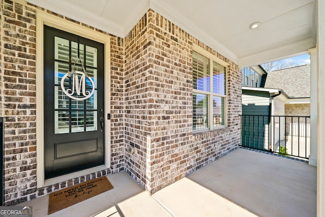 doorway to property with covered porch and brick siding