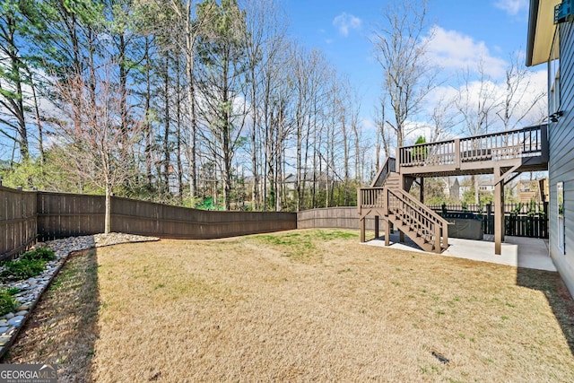 view of yard with a deck, a patio, stairway, and a fenced backyard