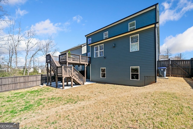 rear view of house with a deck, a patio, a fenced backyard, a yard, and stairway