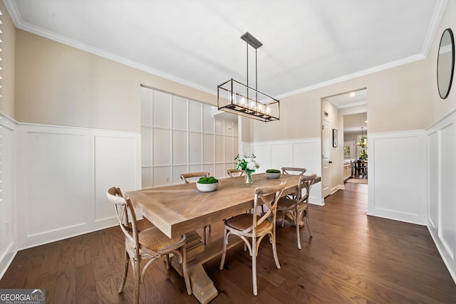 dining area with a wainscoted wall, ornamental molding, dark wood finished floors, an inviting chandelier, and a decorative wall