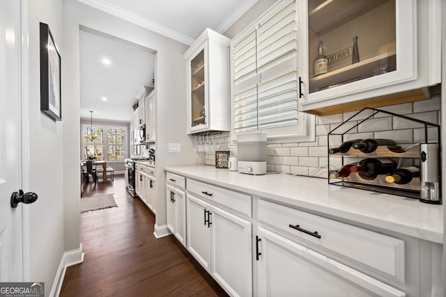 interior space with dark wood-type flooring, white cabinets, crown molding, glass insert cabinets, and stainless steel range with gas stovetop