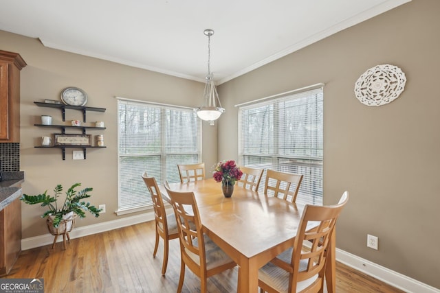 dining area featuring baseboards, light wood-type flooring, and ornamental molding