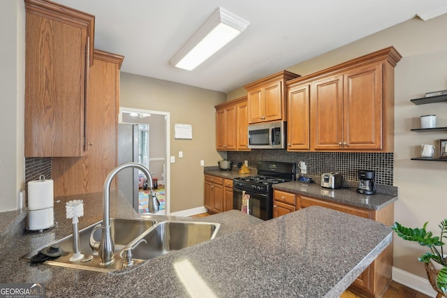 kitchen featuring a sink, stainless steel microwave, tasteful backsplash, dark countertops, and black range with gas stovetop