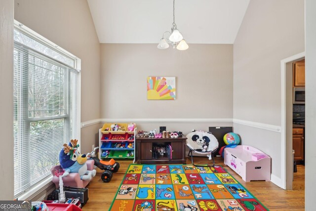 recreation room with an inviting chandelier, lofted ceiling, and wood finished floors