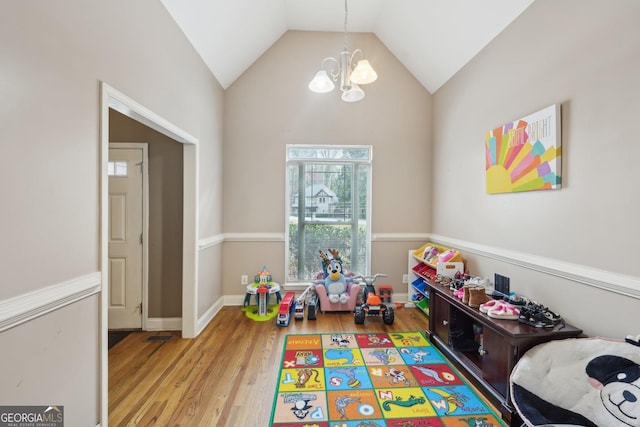 recreation room with a notable chandelier, baseboards, lofted ceiling, and wood finished floors