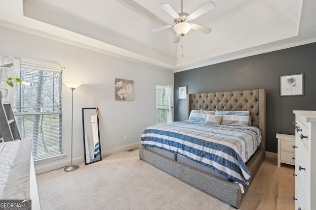 bedroom with a raised ceiling, multiple windows, baseboards, and light carpet