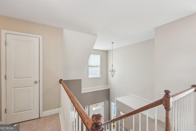 hallway featuring baseboards, an upstairs landing, and light colored carpet