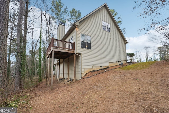 view of home's exterior featuring a wooden deck, a carport, and a chimney