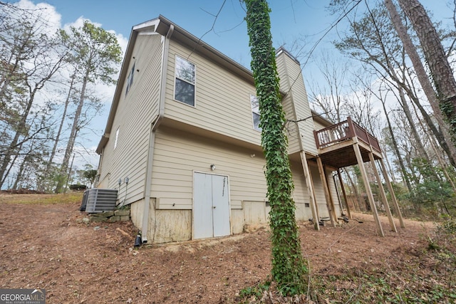 back of house featuring crawl space, central air condition unit, a wooden deck, and a chimney