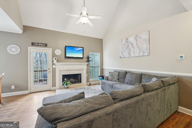 living room featuring baseboards, a ceiling fan, wood finished floors, and a fireplace