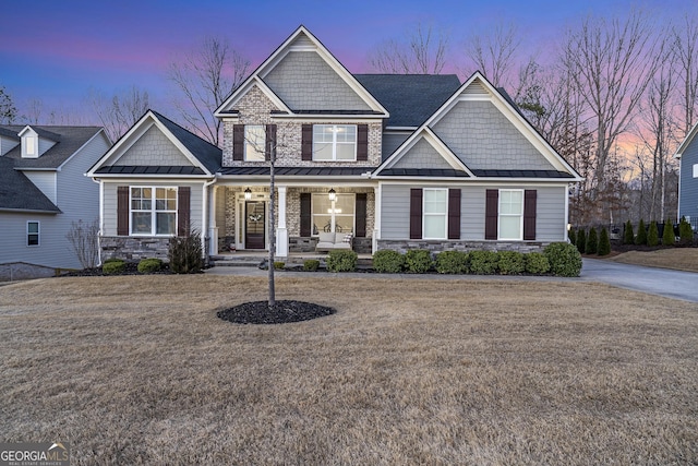 craftsman-style home featuring a standing seam roof, covered porch, and stone siding