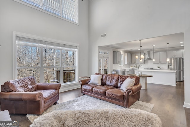 living room featuring dark wood-style floors, visible vents, and a high ceiling