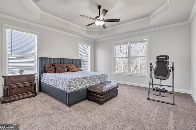 carpeted bedroom featuring a tray ceiling, baseboards, visible vents, and crown molding