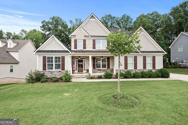 craftsman house with a standing seam roof, a porch, a front lawn, stone siding, and metal roof