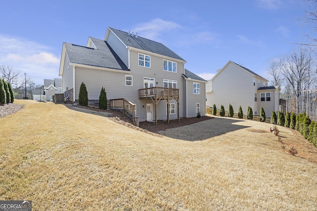 back of property featuring roof with shingles, driveway, a wooden deck, a yard, and central AC