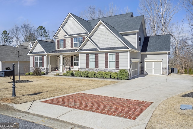 craftsman-style home featuring a porch, roof with shingles, concrete driveway, a front yard, and central AC unit